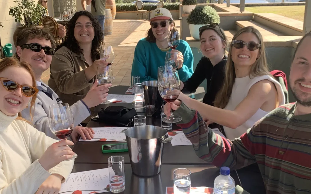 A group of seven friends enjoys a wine tour at a scenic estate vineyard in the Hunter Valley, Australia. They smile and raise their glasses, celebrating a day of tastings and exploration. This experience offers visitors another word for wine tour, such as a vineyard getaway or tasting adventure, showcasing the region’s renowned wines and hospitality.