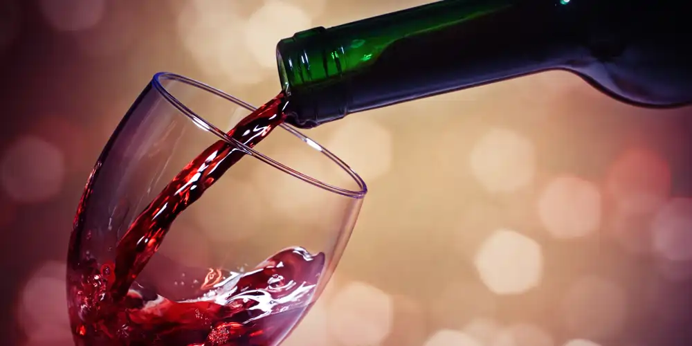 A photo of red wine pouring into a glass, with an abstract background suggesting the pleasure and potential benefits of moderate consumption of red wine for health