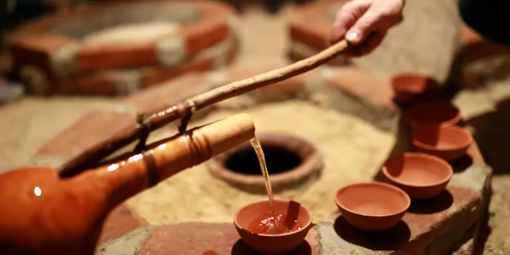 pouring-wine-from-qvevri-using-orshimo-georgia A hand pours wine from a traditional Georgian qvevri using an orshimo, capturing an ancient winemaking ritual linked to the origin of wine