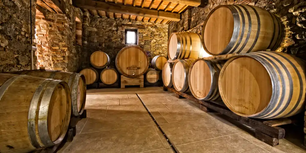 Oak barrels stacked in a stone cellar of a winery, evoking the traditional craftsmanship found throughout the Australian state with the most wineries and highlighting the heritage of renowned Australian wine regions